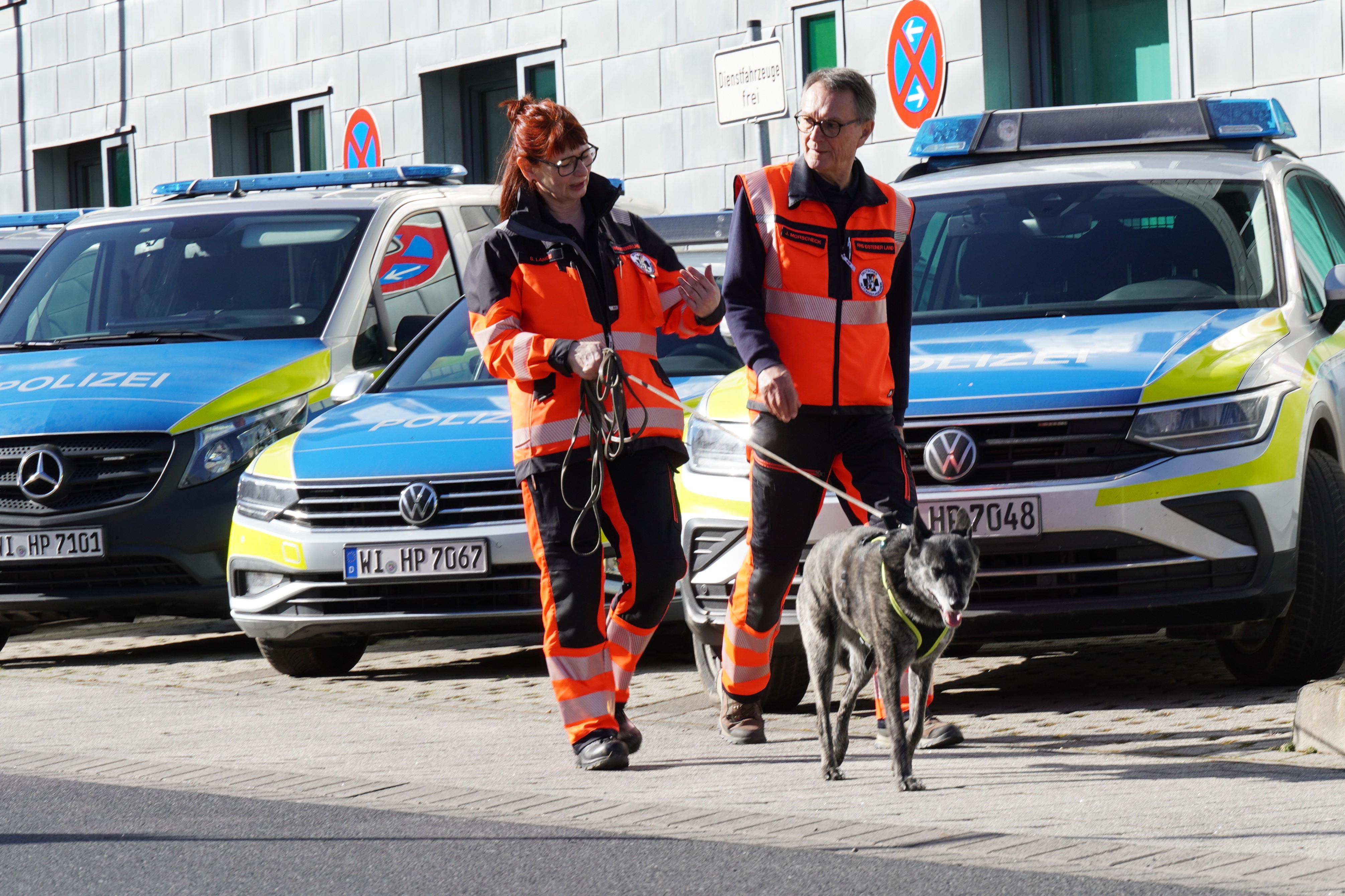 2 Hundeführer mit einem Hund vor der Polizeistation